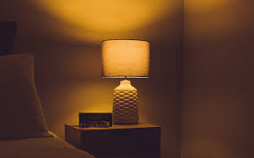 Ceramic bedside table lamp with textured base and cylindrical shade emitting warm glow