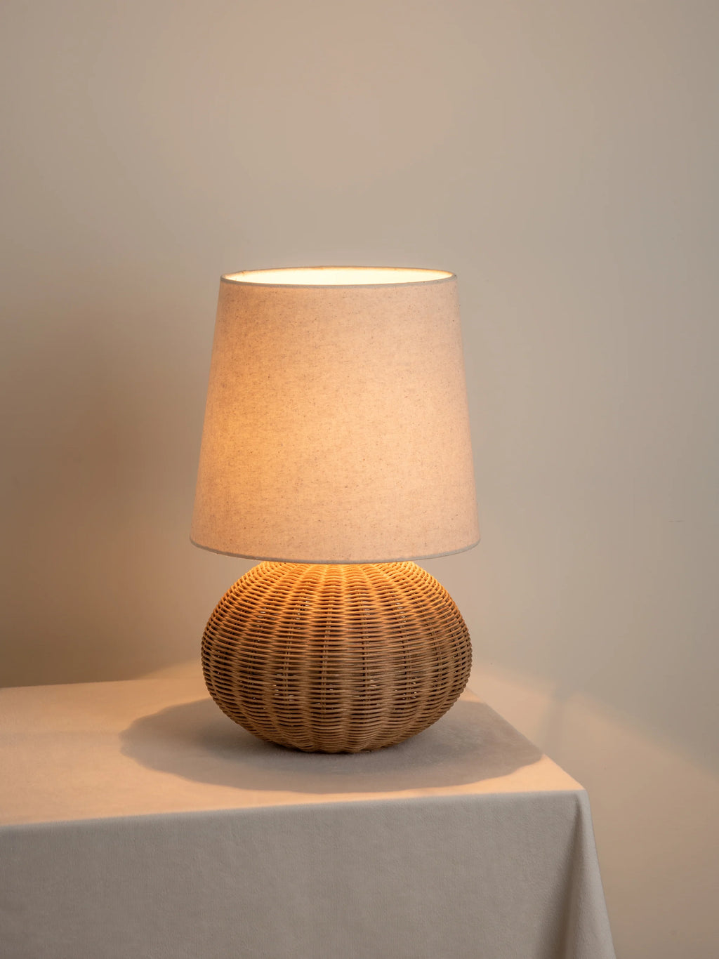 Close-up of hand-woven wicker sphere base of rattan table lamp with linen shade