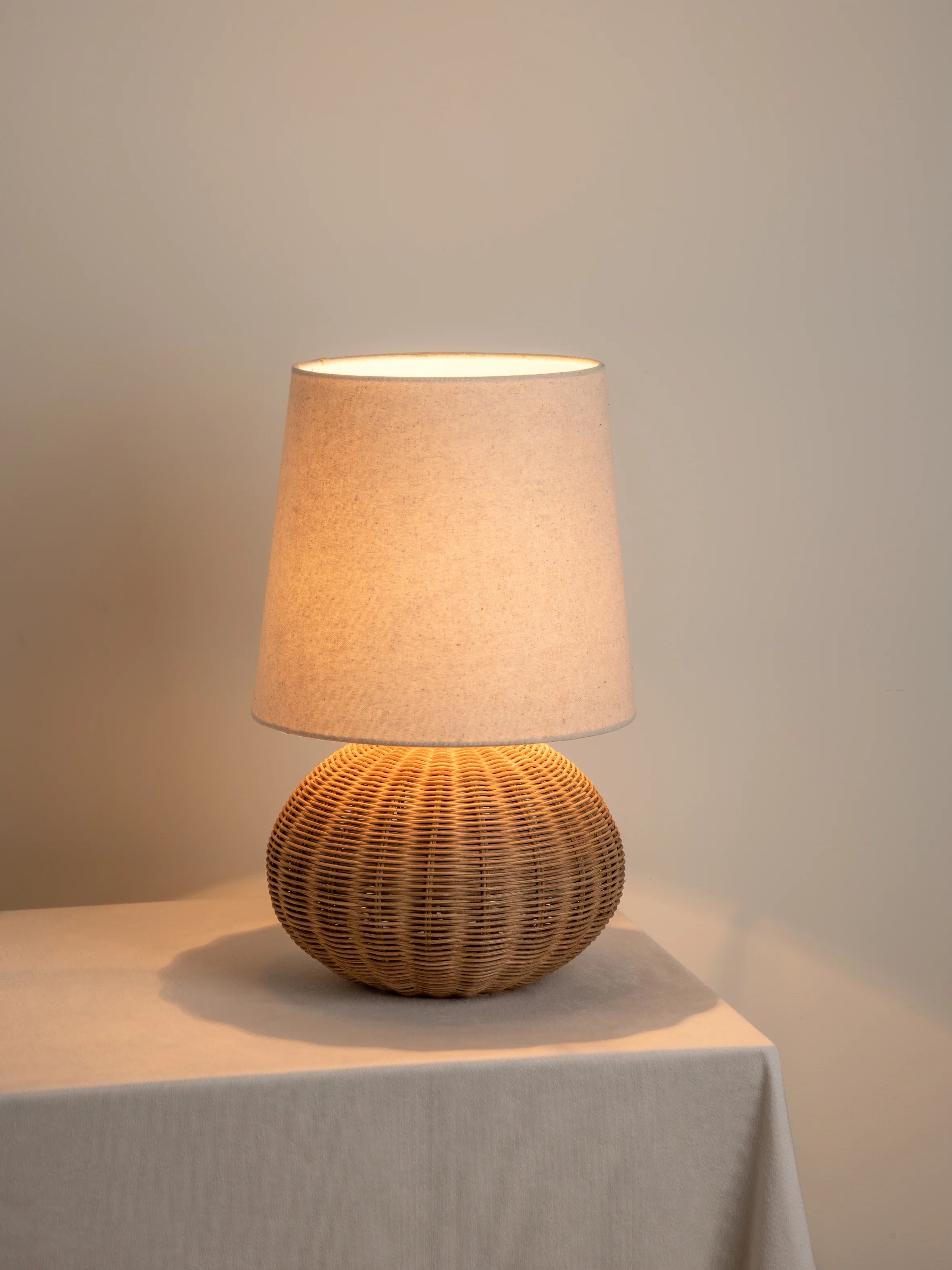Close-up of hand-woven wicker sphere base of rattan table lamp with linen shade